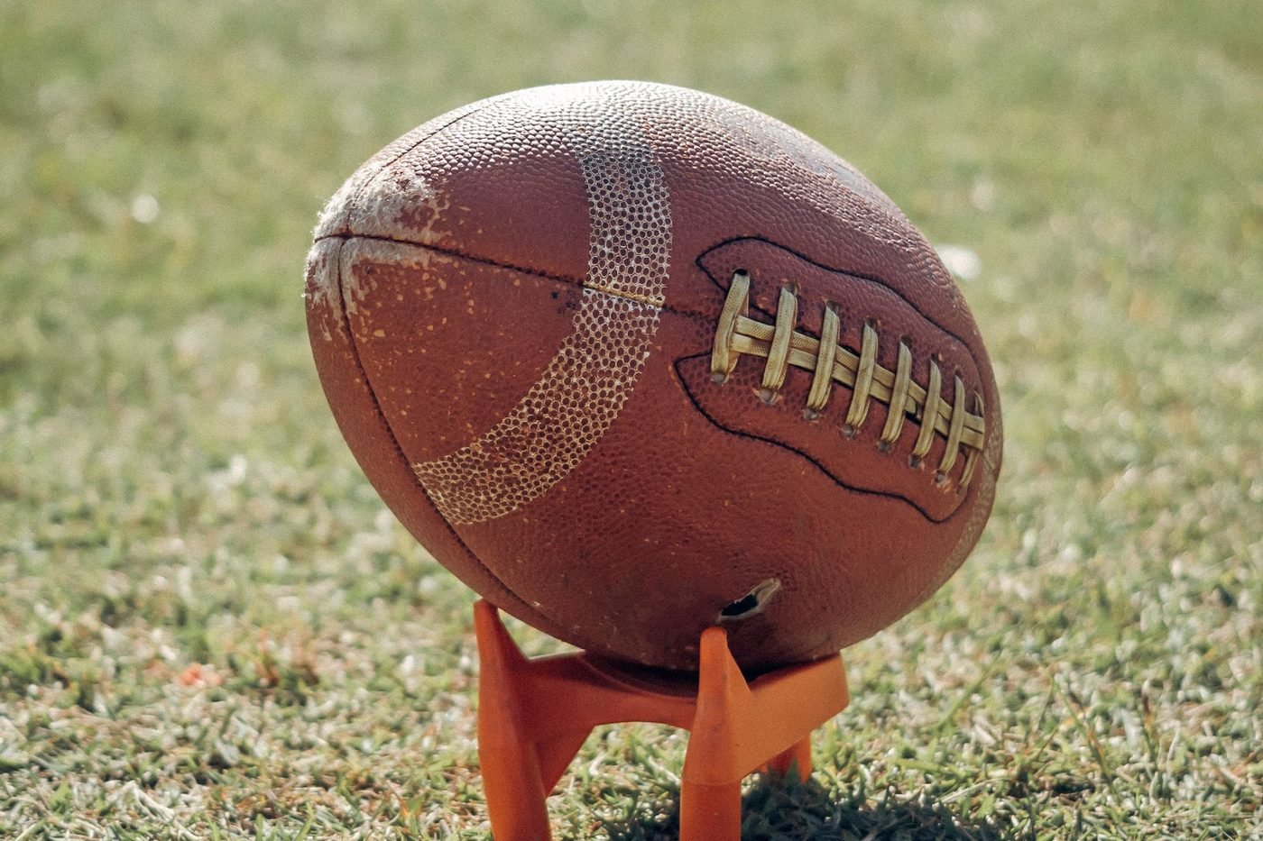 American football resting on a kicking tee on grass (illustrative photo by Gezer Amorim on Pexels, not Bank of America Stadium)