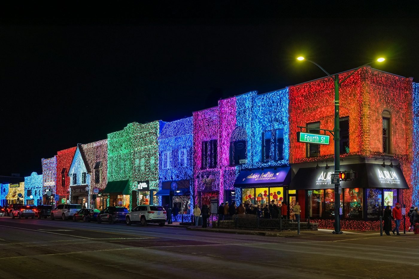 Main-street buildings covered in colored Christmas lights at night (illustrative photo by Brad Switzer on Unsplash, not McAdenville)