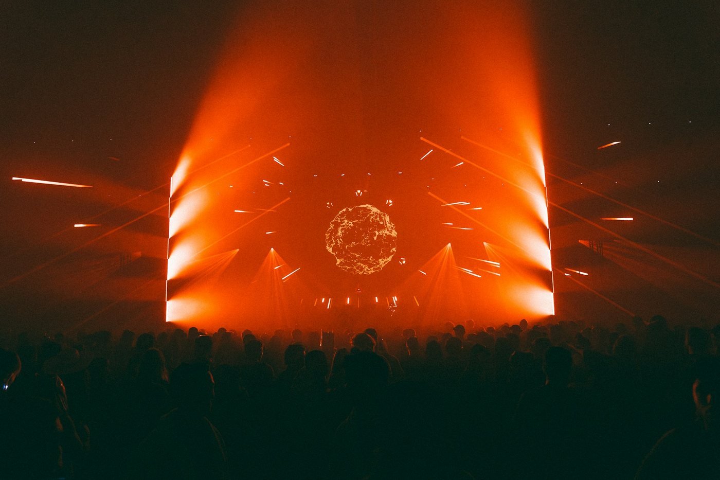 Silhouetted crowd facing an orange-lit arena stage during a concert (illustrative photo by joël Armand Amissa on Unsplash, not Christmas Jam)